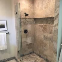 Stone tile shower with frameless glass door