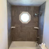 Bathroom tub and shower combo with tile walls and octagon window