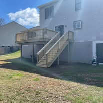 Elevated pressure-treated deck with stairs on back of house