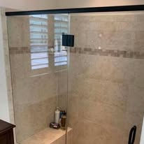 Bathroom shower with travertine tile and frameless glass