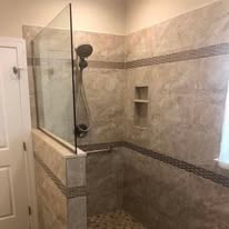 Stone tile shower with frameless glass door