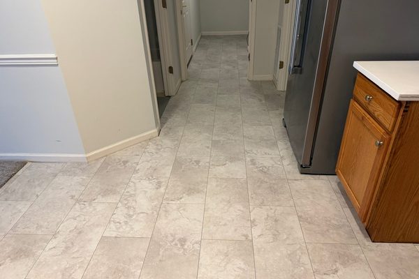 Light stone-look tile laid through a kitchen floor and continuing down the hallway