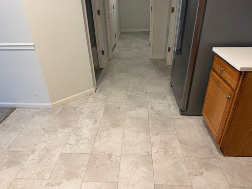 Light stone-look tile laid through a kitchen floor and continuing down the hallway